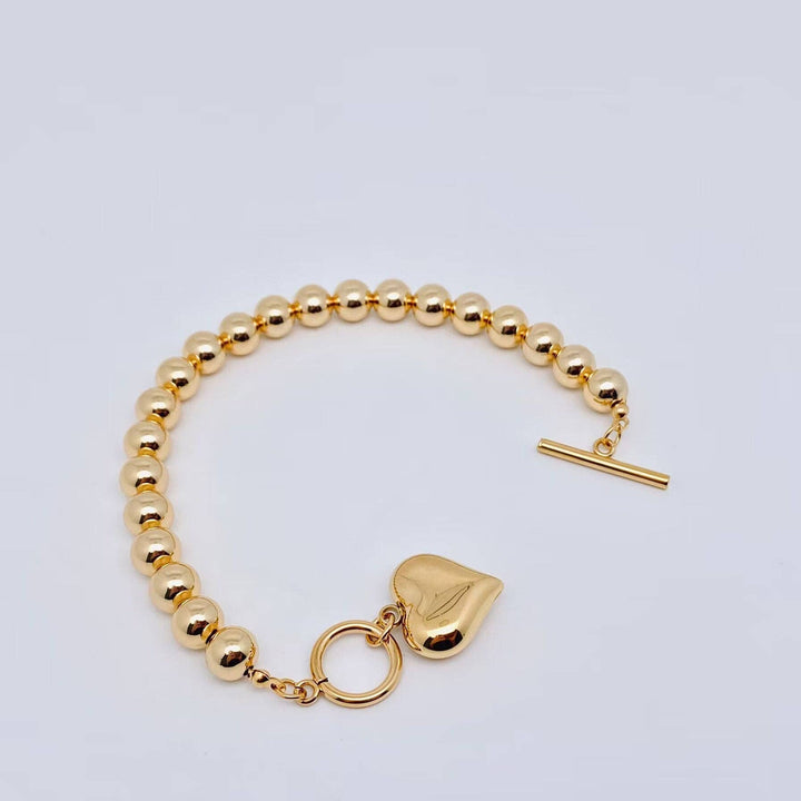 18K gold plated heart charm bracelet with 8MM beads, toggle clasp, and shiny charm. Available in multiple sizes.