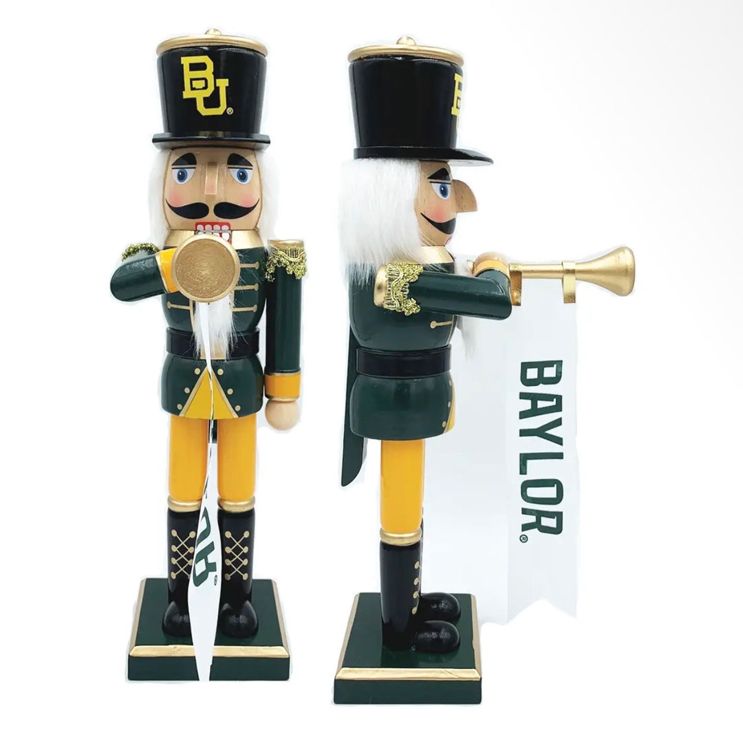 Two 14” handcrafted wood nutcrackers in green and gold uniforms, one playing a trumpet with a banner and one holding a drum.