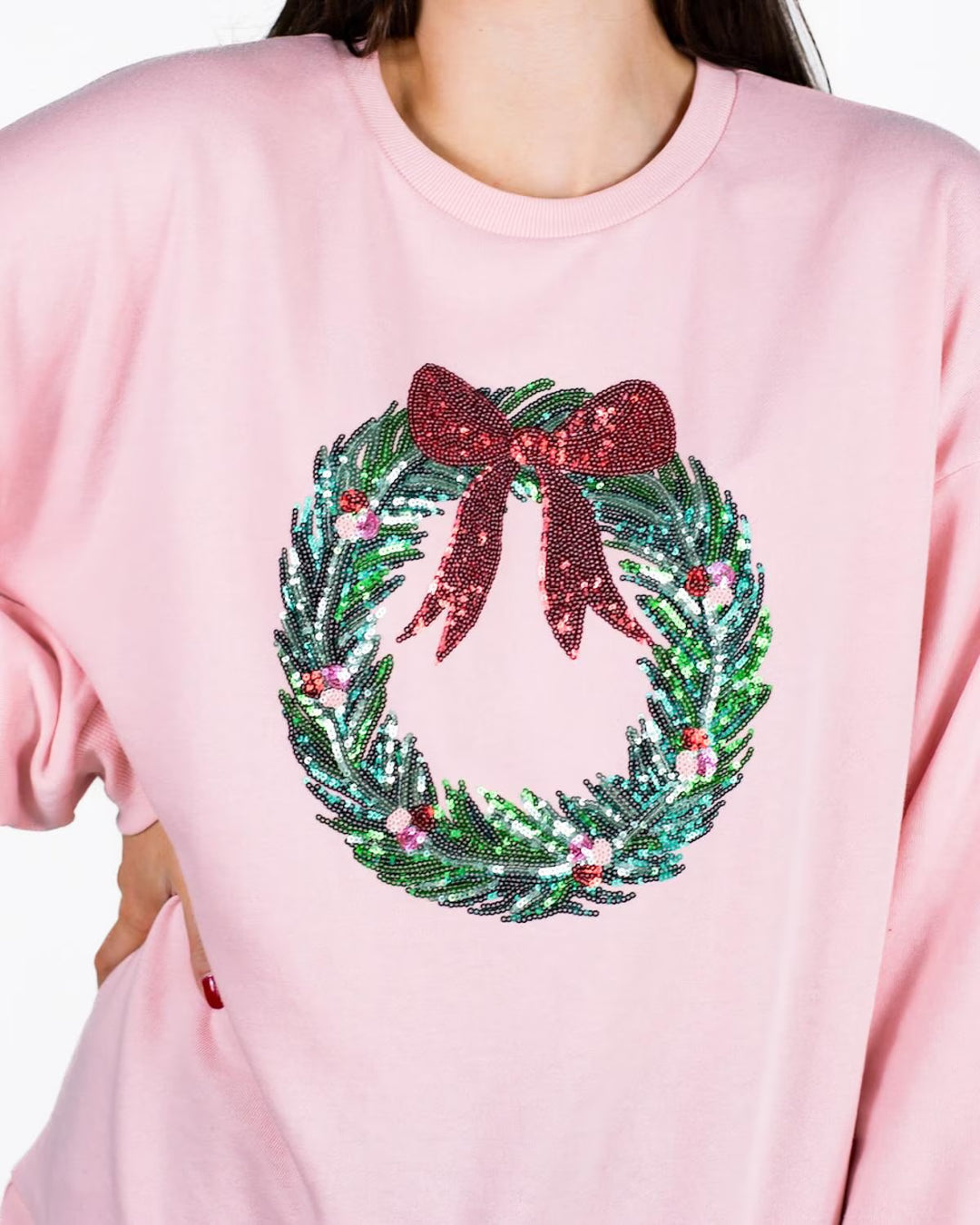 Clara Wreath Sequin Sweatshirt in light pink with sequin wreath and red bow on front. Available in sizes XS–XL.