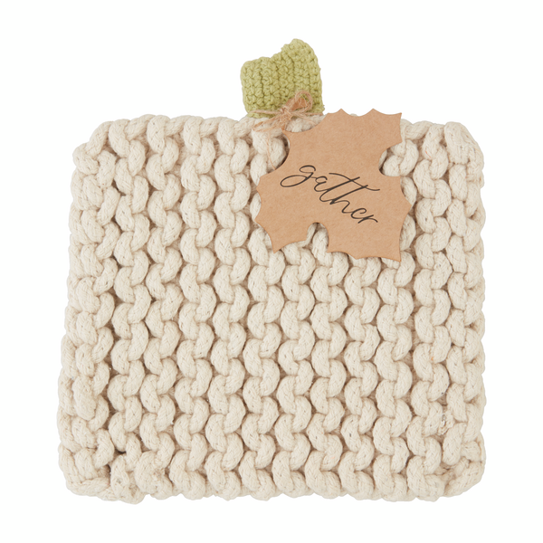 Off-white pumpkin-shaped knit trivet with a light green stem and a “gather” tag.