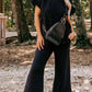 A woman stands outdoors wearing a stylish navy blue Quilted Short Sleeve Wide Leg Pants Set, available in multiple sizing options, with a black crossbody bag and white sneakers.