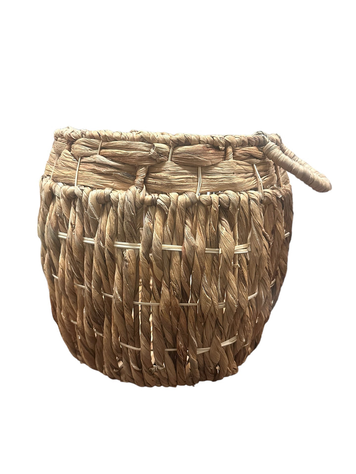 Round, thickly woven basket of natural light brown fibers with a side handle. Available sizes: small, medium, large.