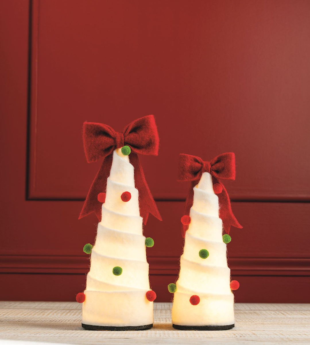 Two LED felted wool pom-pom Christmas trees, white with red and green accents and internal LED lights.