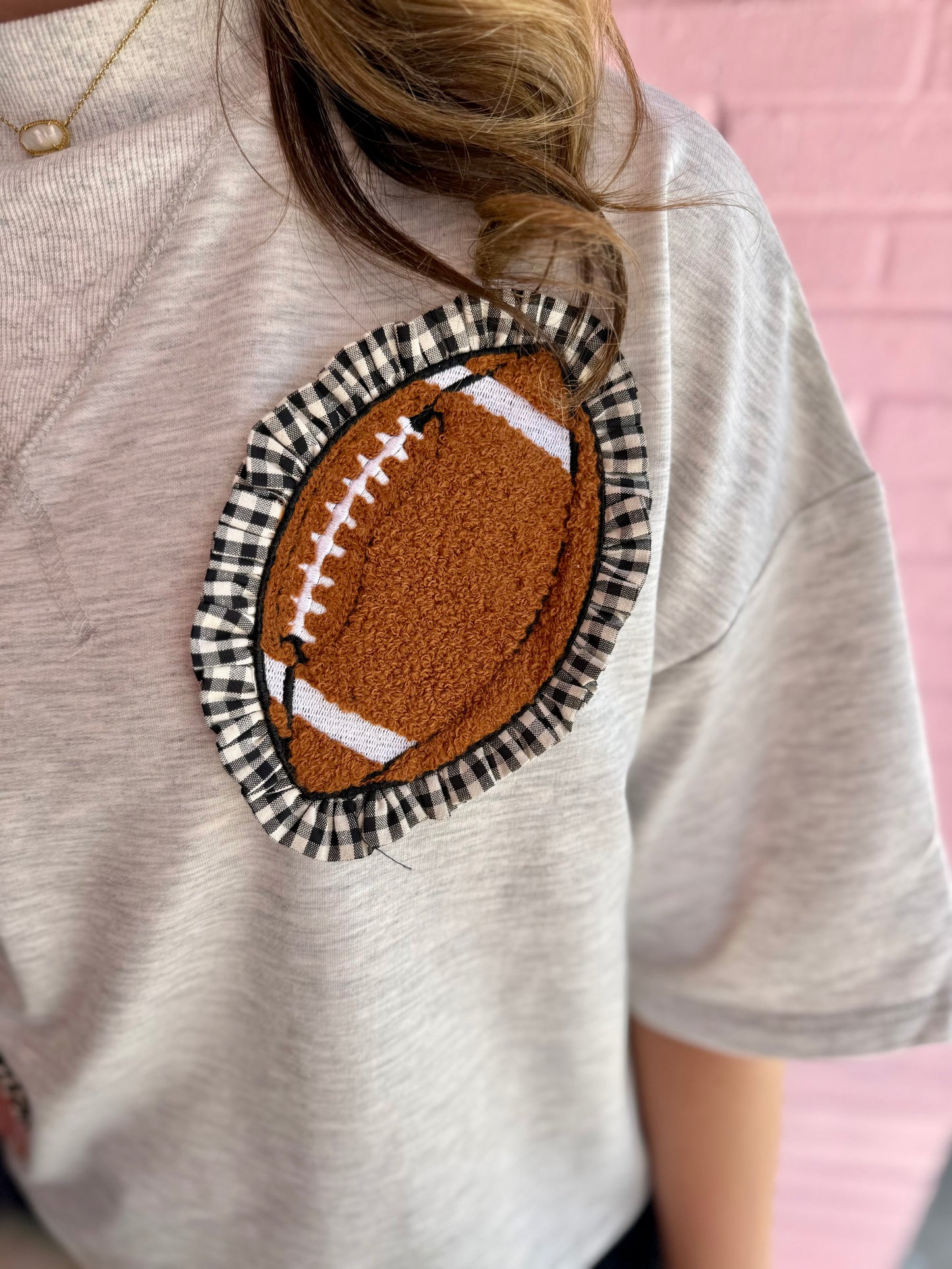 Gameday Gingham Football Patch Top: cropped, oversized t-shirt with chenille football patch and black-and-white plaid ruffle. Available in sizes S-XL.