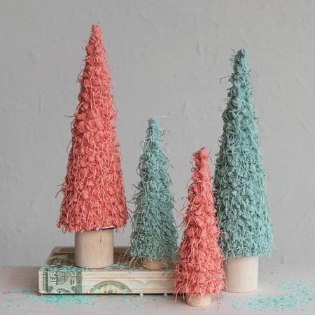 Small fabric conical tree decorations with wood bases in pink and teal.