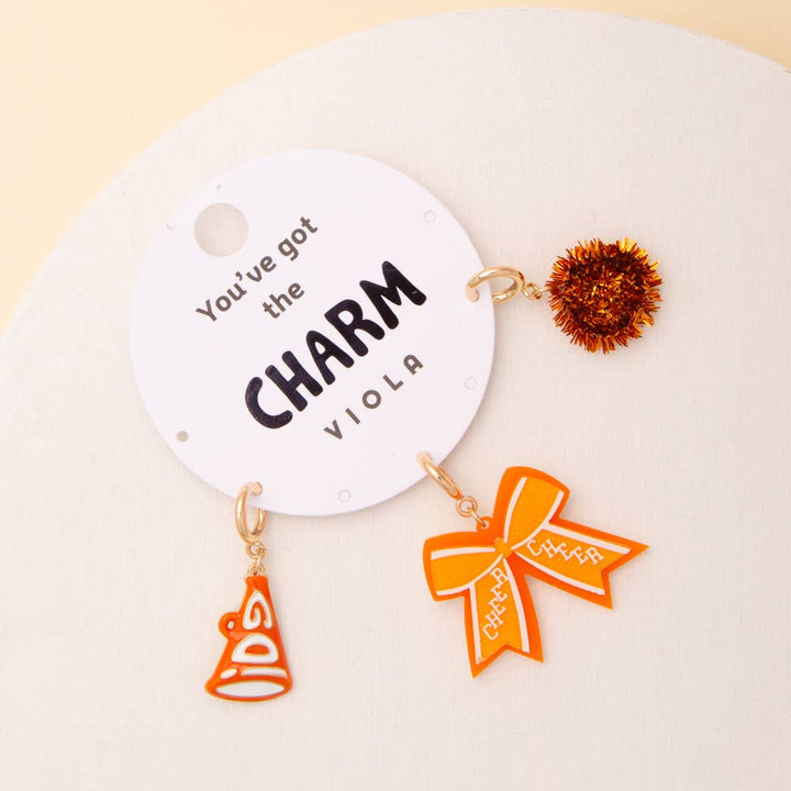 Charm Set includes pom pom, megaphone, and glittered bow charms. Available in one size. Carded with “You’ve got the CHARM VIOLA.”.