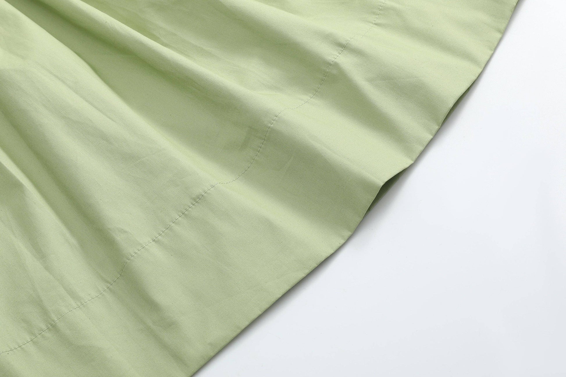 Close-up of pistachio green fabric with visible stitching and gentle folds, from the Mallard Duck Smocked Bishop Dress available in size 4T.