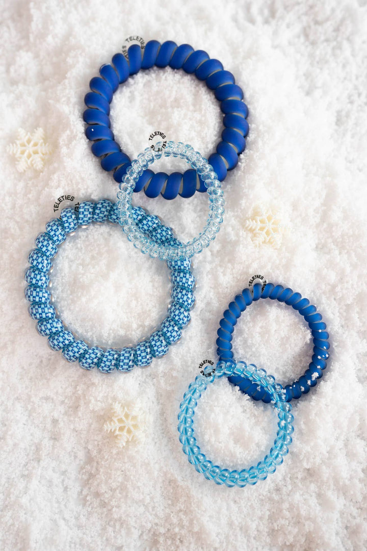 Four blue spiral hair coils in various sizes and shades, with matte and transparent finishes from the Mazel! Mix Pack.