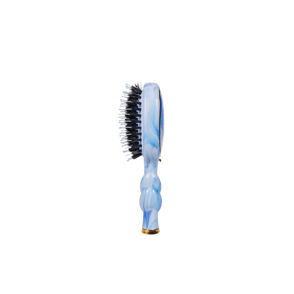 The Mini Boar Brush | Tide & True, with a blue marble-patterned handle and black and white natural boar bristles. Available in travel size.