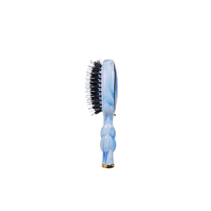 The Mini Boar Brush | Tide & True, with a blue marble-patterned handle and black and white natural boar bristles. Available in travel size.