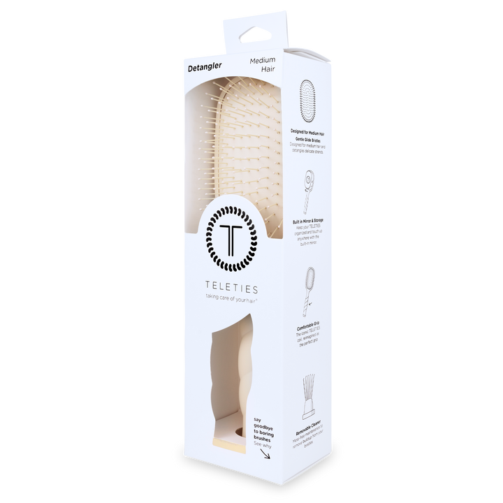 White rectangular box with clear window shows a tan Detangler Hair Brush for medium hair; simple illustrations and instructions on the side. Available in size for medium hair.