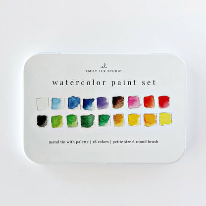 White metal tin labeled “Watercolor paint set 18 colors with brush” from Emily Lex Studio contains a compact palette with 18 vibrant colors and a size 6 round brush in petite sizing.