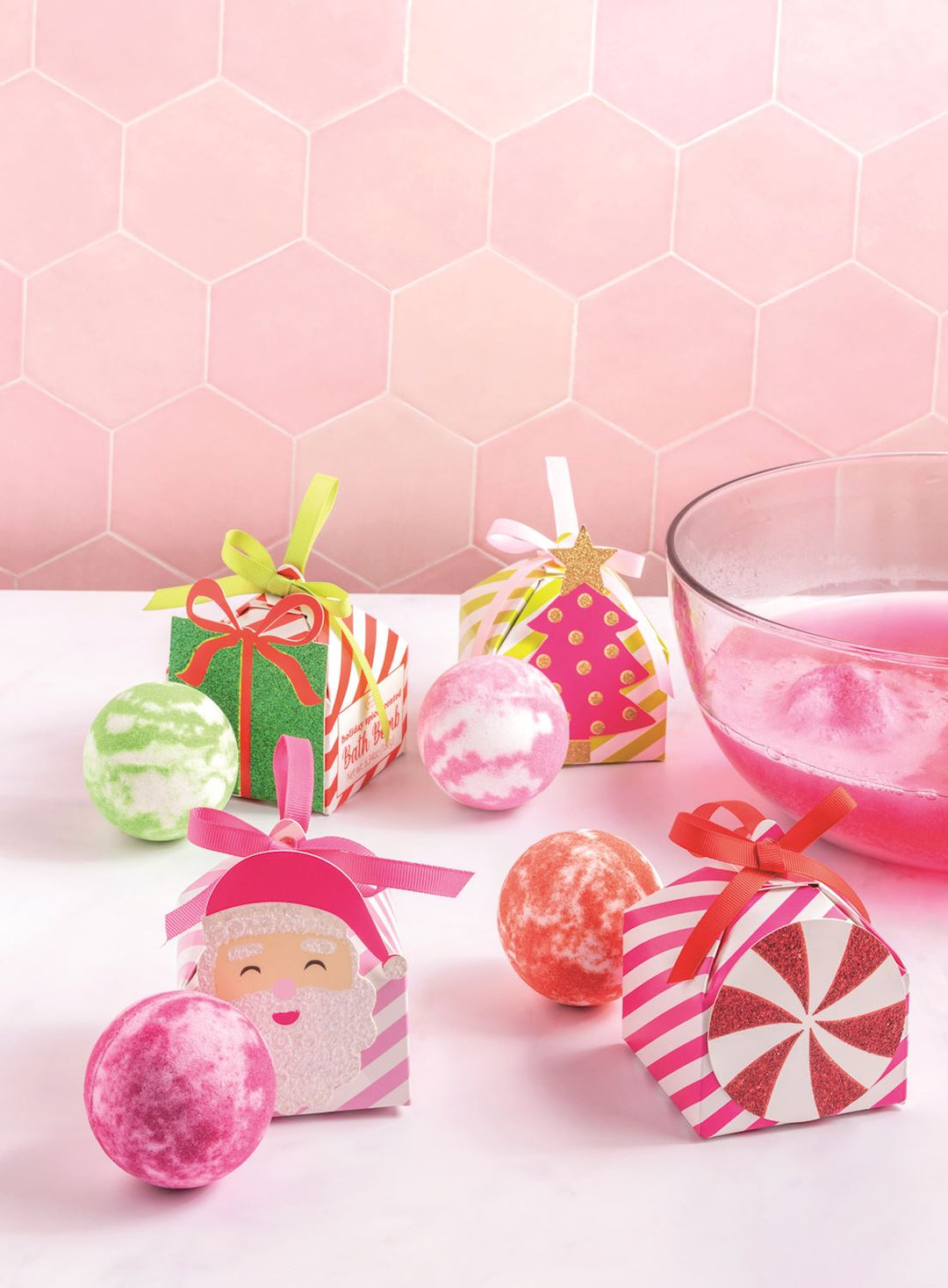 Four decorative holiday-themed gift boxes tied with ribbons and three Pastel Holiday Bath Bombs.