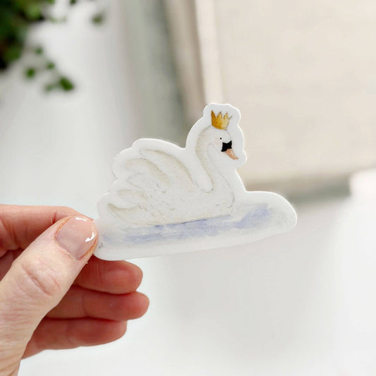 White swan with gold crown on light blue water; watercolor sticker. Available sizes: 2", 3".