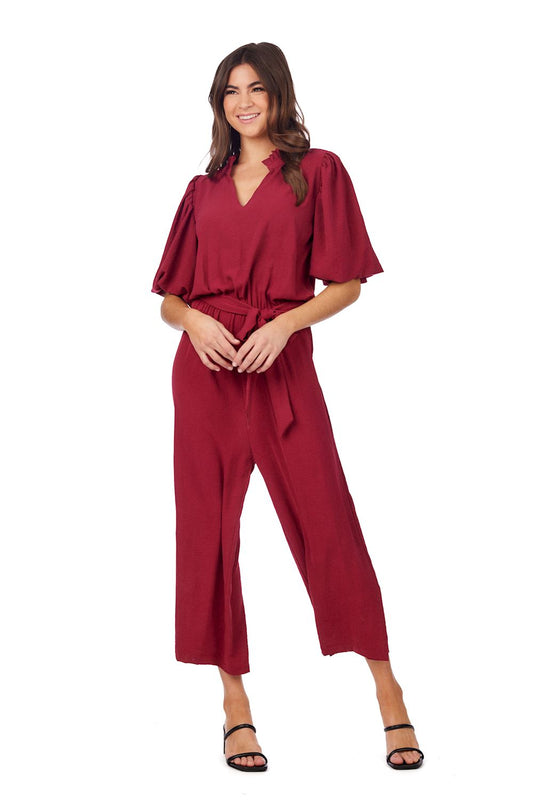 Deep red Annalise Jumpsuit: short sleeves, V-neck, polyester, removable waist tie. Available in sizes XS–XL.
