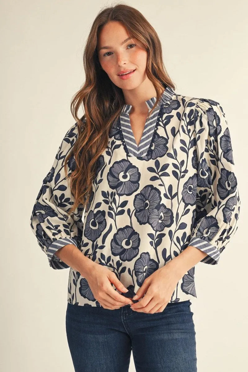 Bonnie Ruffle Floral Blouse: cream with navy floral print, ruffled neckline. Available in XS–XL.