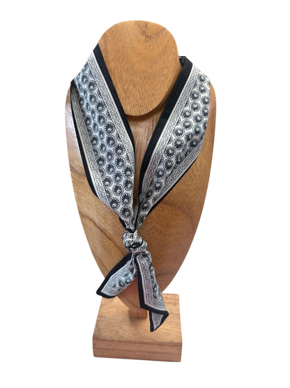 The Scarf Necklace features a black and white pattern. Multi-functional. Available in small, medium, and large sizes.