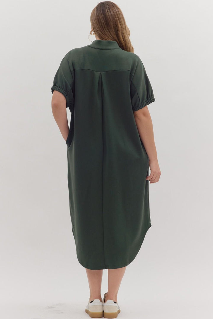 Dark green Collie Midi Dress with V-neck, band collar, short sleeves, gathered cuffs, back pleat, and lightweight knit construction. Available in all standard sizes.