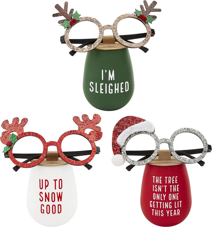 Three Christmas silicone wine glasses featuring reindeer, holly, and Santa hat sunglasses, printed with “I’m Sleighed,” “Up to Snow Good,” and “The Tree Isn’t the Only One Getting Lit This Year.”.