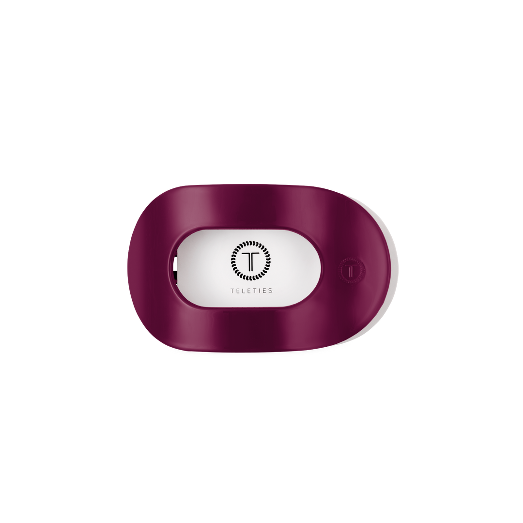 Maroon, oval-shaped plastic hair tie holder with open slot and TELETIES logo in black; available in multiple sizes.