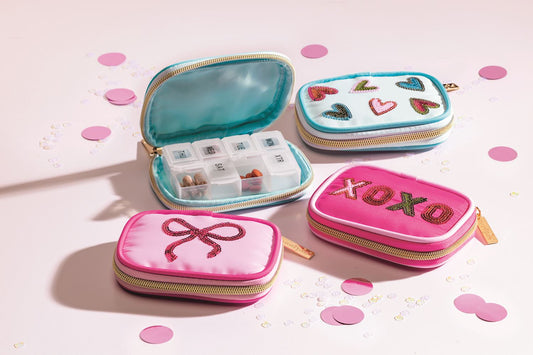 Sequin pill cases in heart, bow, and "XOXO" designs with a weekly organizer inside. Available in small and large sizes.