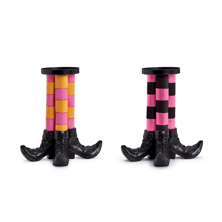 Set of two pillar candleholders shaped like witch legs with black shoe bases; one with yellow and pink glitter checkered legs, one with black and pink checkered legs. Sizes available: standard pillar candle size.
