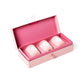 Pink checkered box with button clasp holding three sparkling rosé candles, each wrapped in white paper. Sizes: small, medium, large.