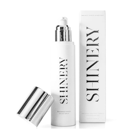 White bottle of Shinery Jewelry Wash® with silver pump and cap, SHINERY logo in silver. Available in 100ml and 200ml sizes.