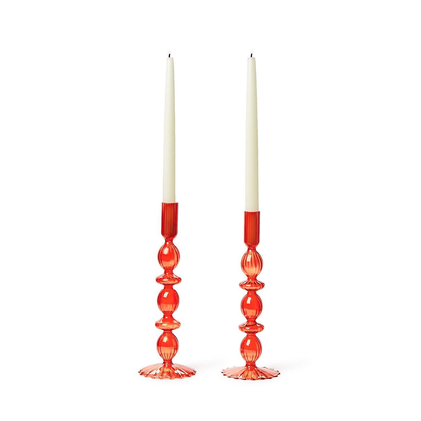 Two tall white taper candles in hand-blown glass candlesticks, red with an ornate ribbed pattern. Sizes: Standard height for taper candles.