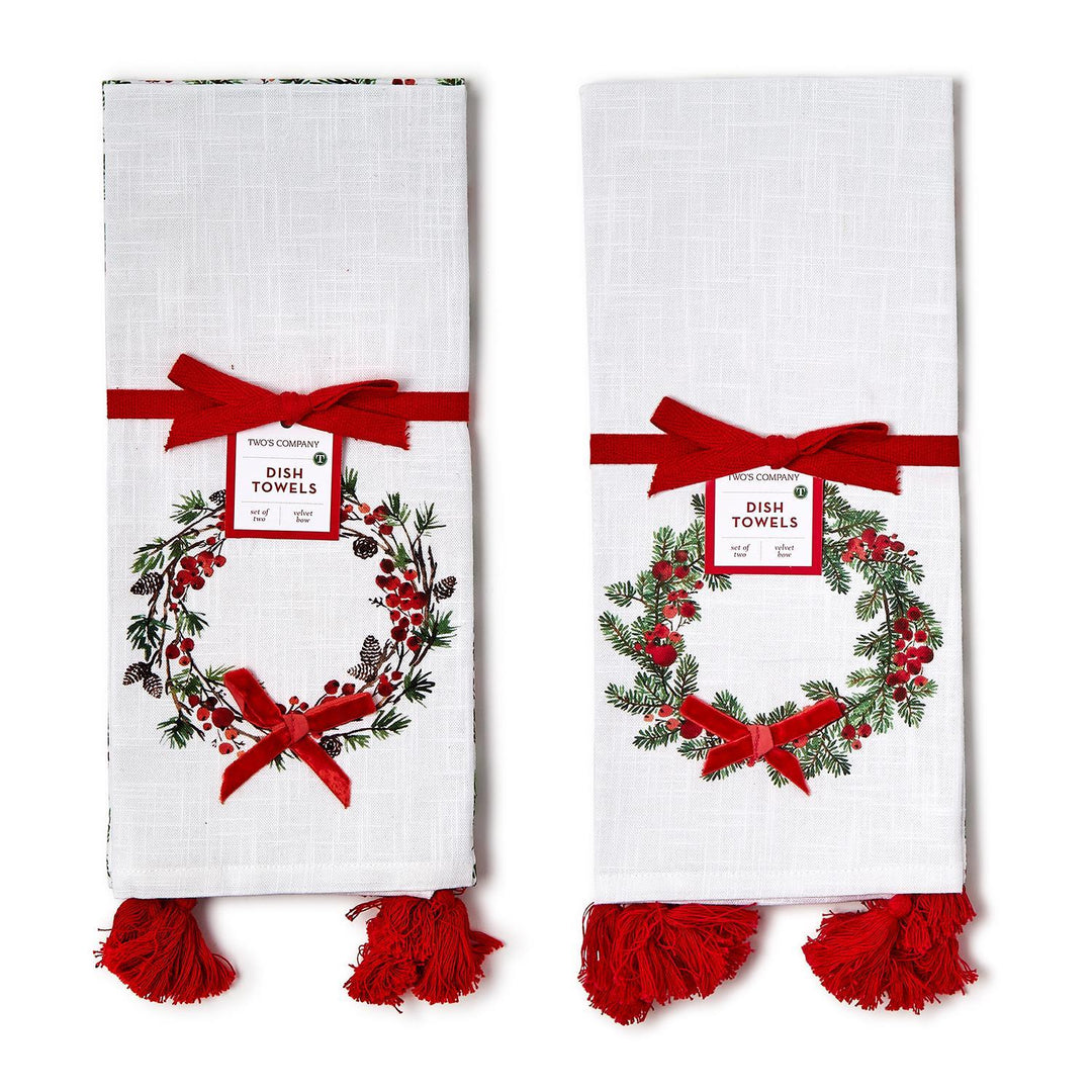 Merry Berry set of 2 white dish towels featuring a holiday wreath pattern of pine branches, pinecones, and red berries, accented with red velvet bows and tassels.
