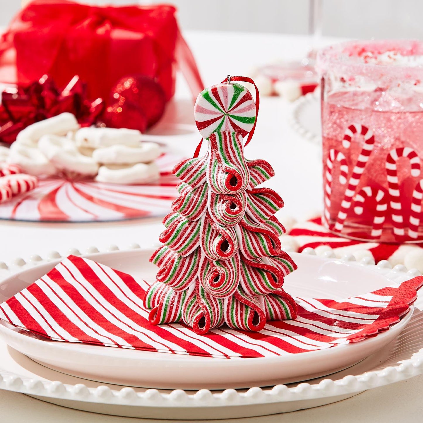 A Christmas tree-shaped ornament made from red, white, and green striped ribbons. Sizes available: Small, Medium, Large.