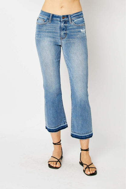 Judy Blue Mid Rise Release Hem Cropped Bootcut Jeans, light blue, faded wash, frayed hem. Available in sizes 24-32.