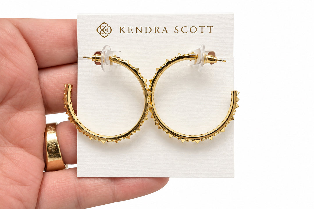 Gold hoop earrings with sculptural spikes and clear cubic zirconia accents, displayed on a white Kendra Scott card. Sizes available: small, medium, large.