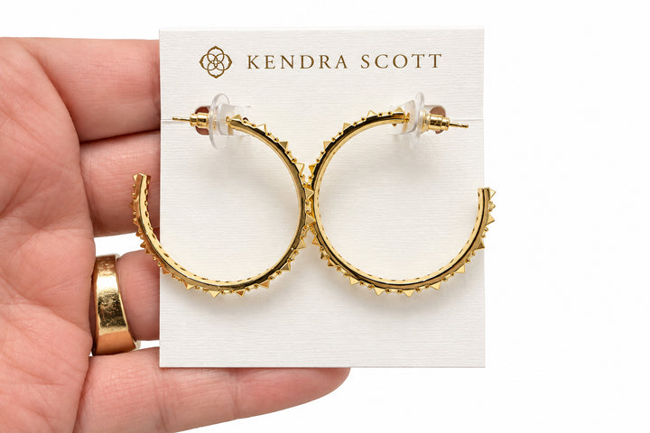 Gold hoop earrings with sculptural spikes and clear cubic zirconia accents, displayed on a white Kendra Scott card. Sizes available: small, medium, large.