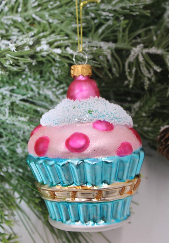 Glass cupcake ornament with pink frosting, white sprinkles, and a blue fluted base.