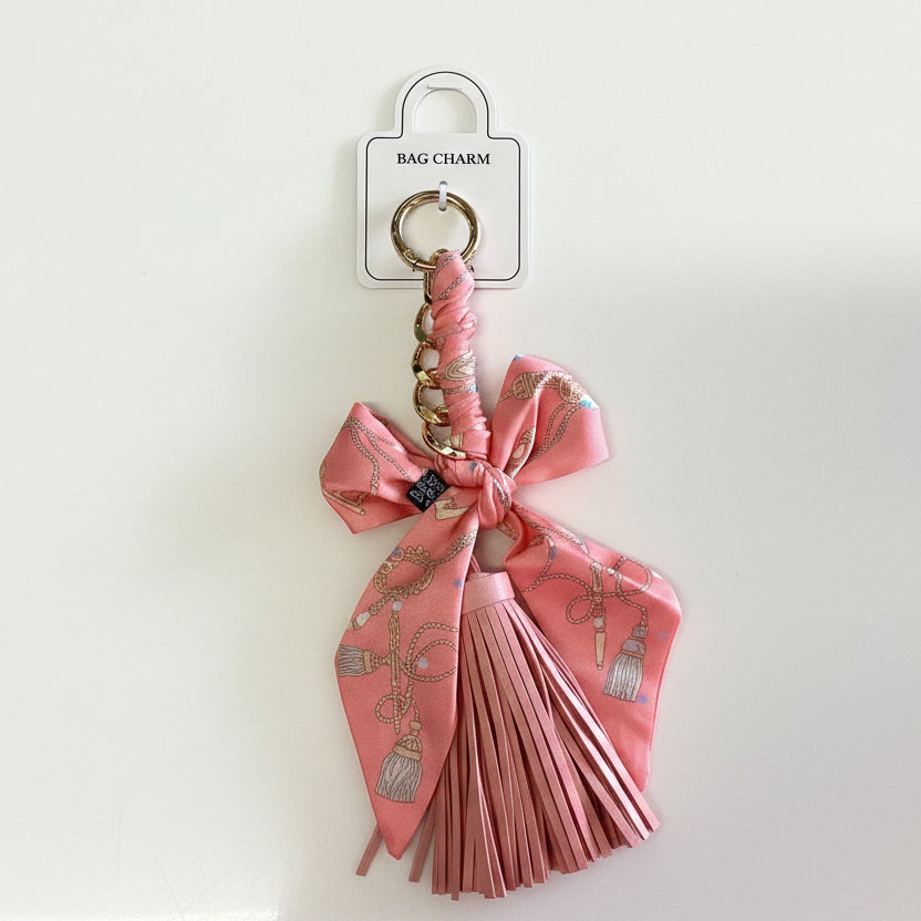 Pink bow tassel bag charm with gold keyring, pink ribbon, and chain accents. Size options not specified.