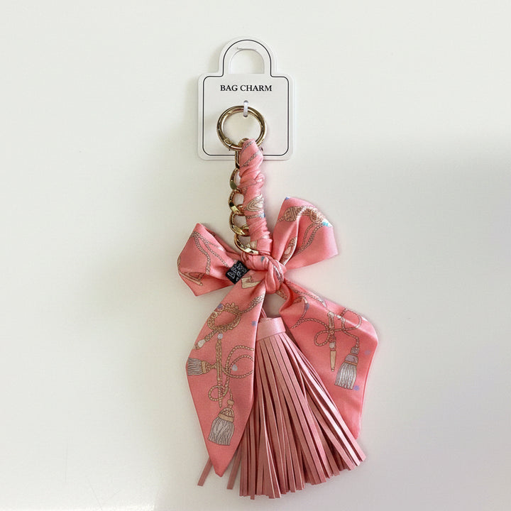 Pink bow tassel bag charm with gold keyring, pink ribbon, and chain accents. Size options not specified.