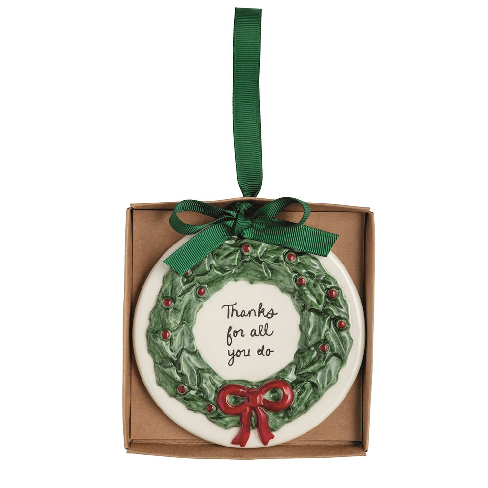 Round, hand-painted ceramic Thank You ornament featuring a holly wreath, a red bow, and the text “Thanks for all you do,” hanging from a green ribbon.