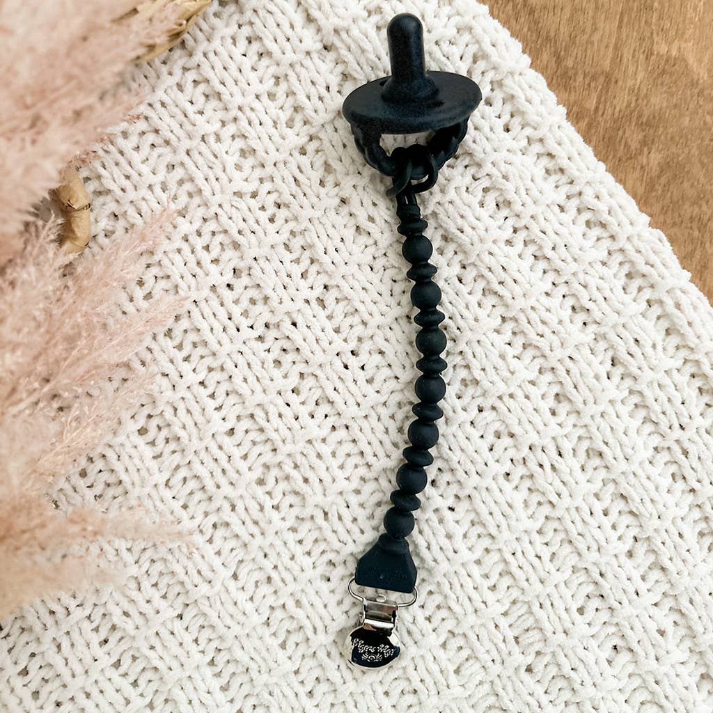 Black Sweetie Strap™ Silicone One-Piece Pacifier Clips: Hero Blue Beaded with food grade silicone beads attached to a white textured blanket.