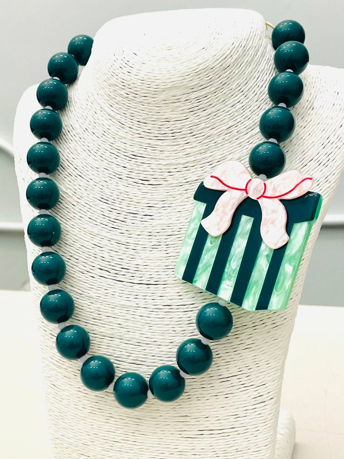 The HOLIDAY - Beaded Gift Necklace (green) BNK1215 features chunky green beads and a striped green gift box pendant with a pink bow. Available in multiple sizes.