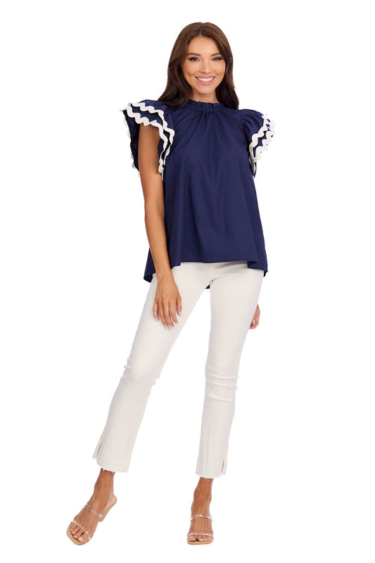 The Angie Ric Rac Top is a navy blouse with a ruffle neckline and flutter sleeves. Available sizes: XS, S, M, L, XL.