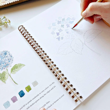Flowers Watercolor Workbook with spiral binding, partially completed floral art, color swatches, and painting instructions. Sizes: N/A.
