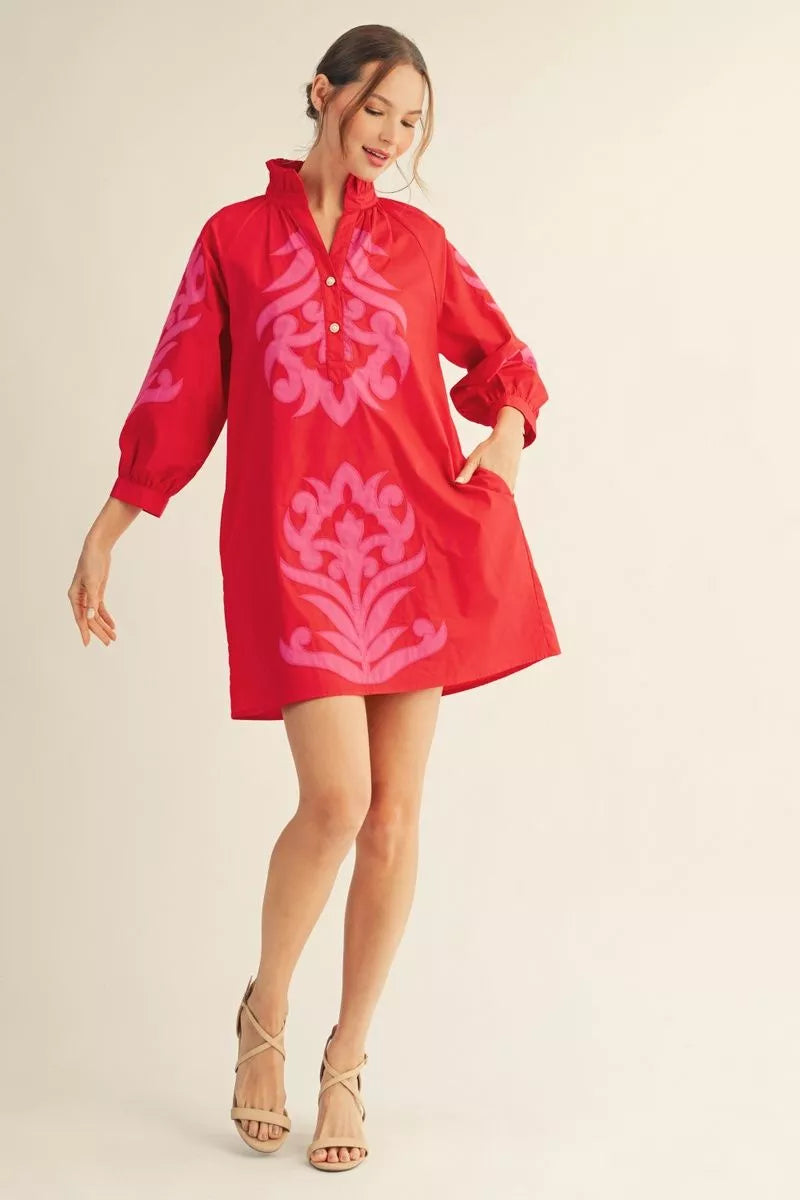 Red cotton shift dress with pink baroque appliqué, ruffled neckline, puffy sleeves, short hem. Sizes: XS–XL.