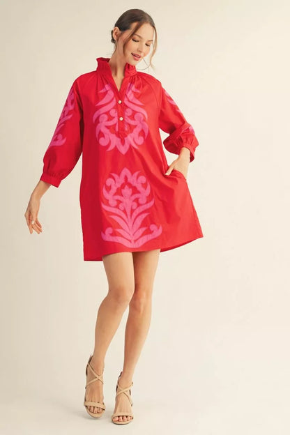 Red cotton shift dress with pink baroque appliqué, ruffled neckline, puffy sleeves, short hem. Sizes: XS–XL.