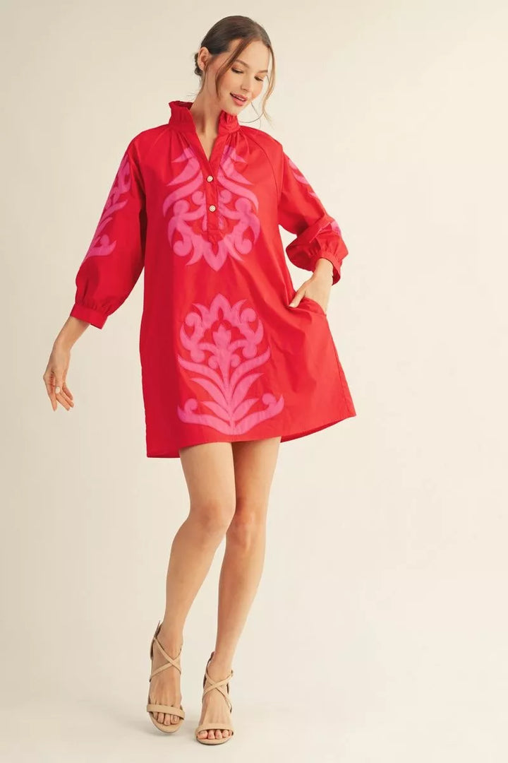 Red cotton shift dress with pink baroque appliqué, ruffled neckline, puffy sleeves, short hem. Sizes: XS–XL.
