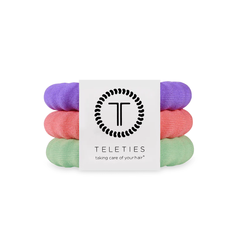 Three Teleties nylon hair ties in purple, pink, and mint green with logo label; available in small, medium, and large sizes.