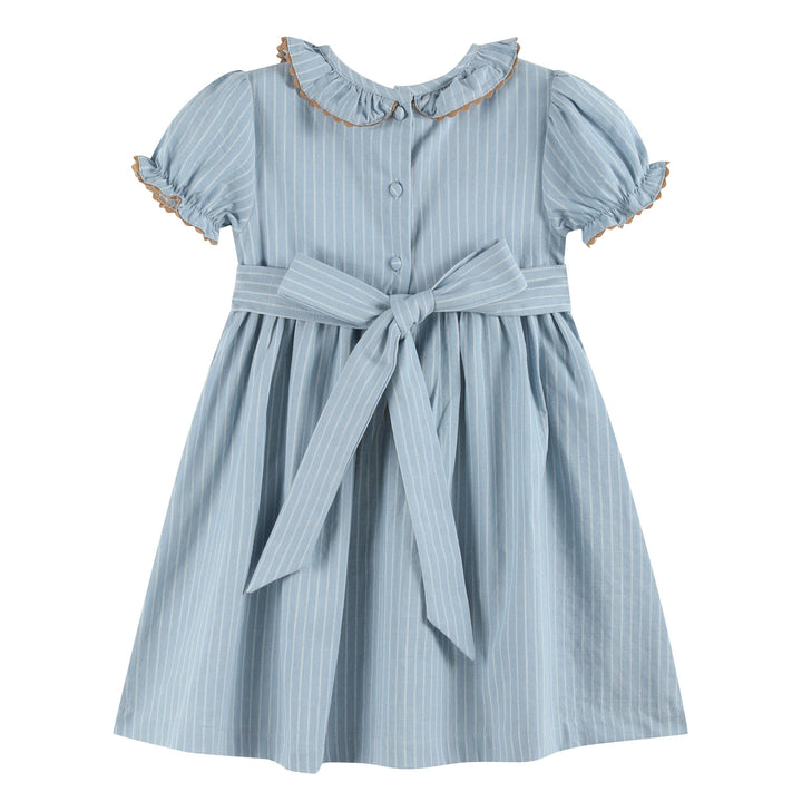 Light blue girls’ dress with white pinstripes, smocked ruffle collar with brown trim, puffed sleeves edged in brown ruffles, and a large waist bow. Size: 12-18M.