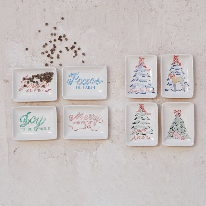 Eight rectangular stoneware dishes with Christmas tree and dog holiday motifs and seasonal text.