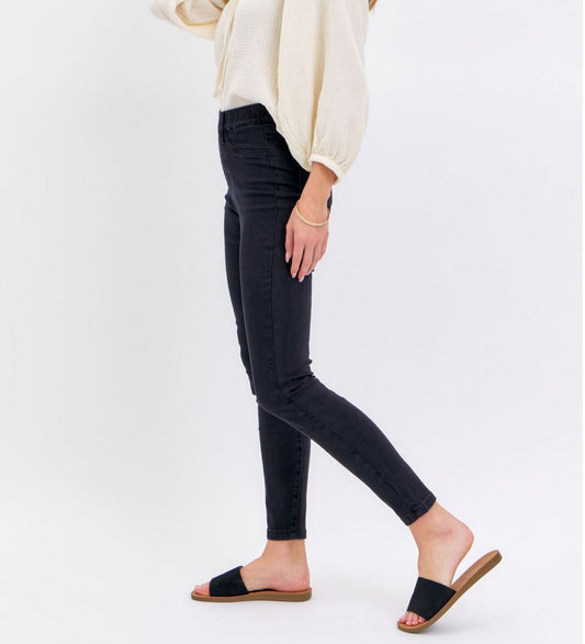 Cream-colored long-sleeved blouse. Judy Blue High Waist Pull On Shield Pocket Skinny Jeans in black. Available sizes: 0-24W. Black open-toe sandals.