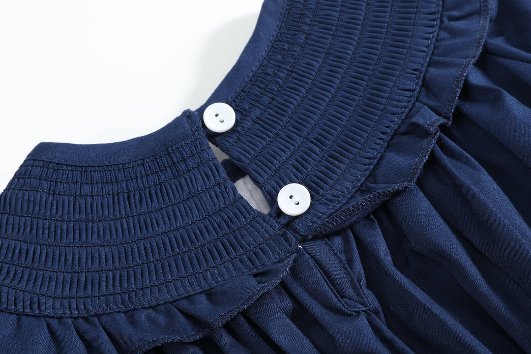 Navy blue Blue Nativity Smocked Ruffle Romper with pleated textured collar and two white buttons at the back; size 3-6M.